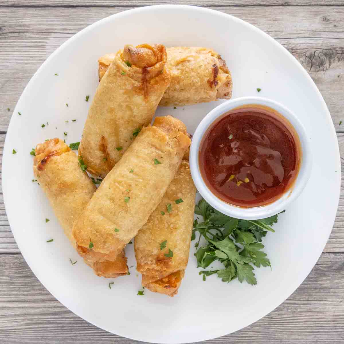 Eggrolls on a white plate with sweet and sour sauce.