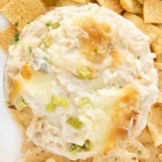 crab rangoon dip in bowl on a white platter with crackers and tortilla dippers.