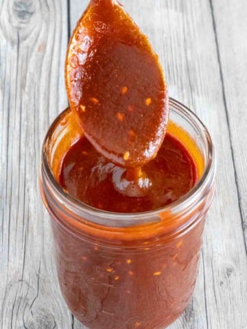 Gochujang Sauce in a glass jar with a spoon coming out.