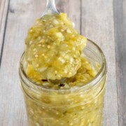 Mexican Salsa Verde in a glass jar with a spoon coming out.