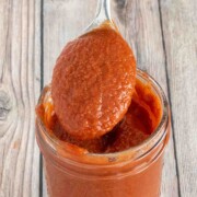 Taco sauce in a glass jar with a spoon coming out.