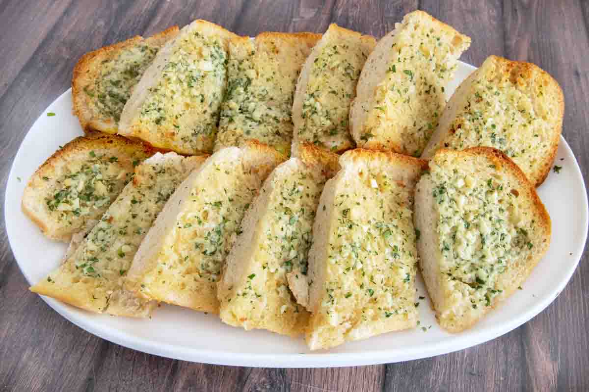 Sliced garlic bread on a white platter.