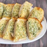 Sliced garlic bread on a white platter.