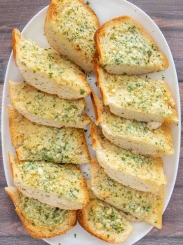 Sliced garlic bread on a white platter.