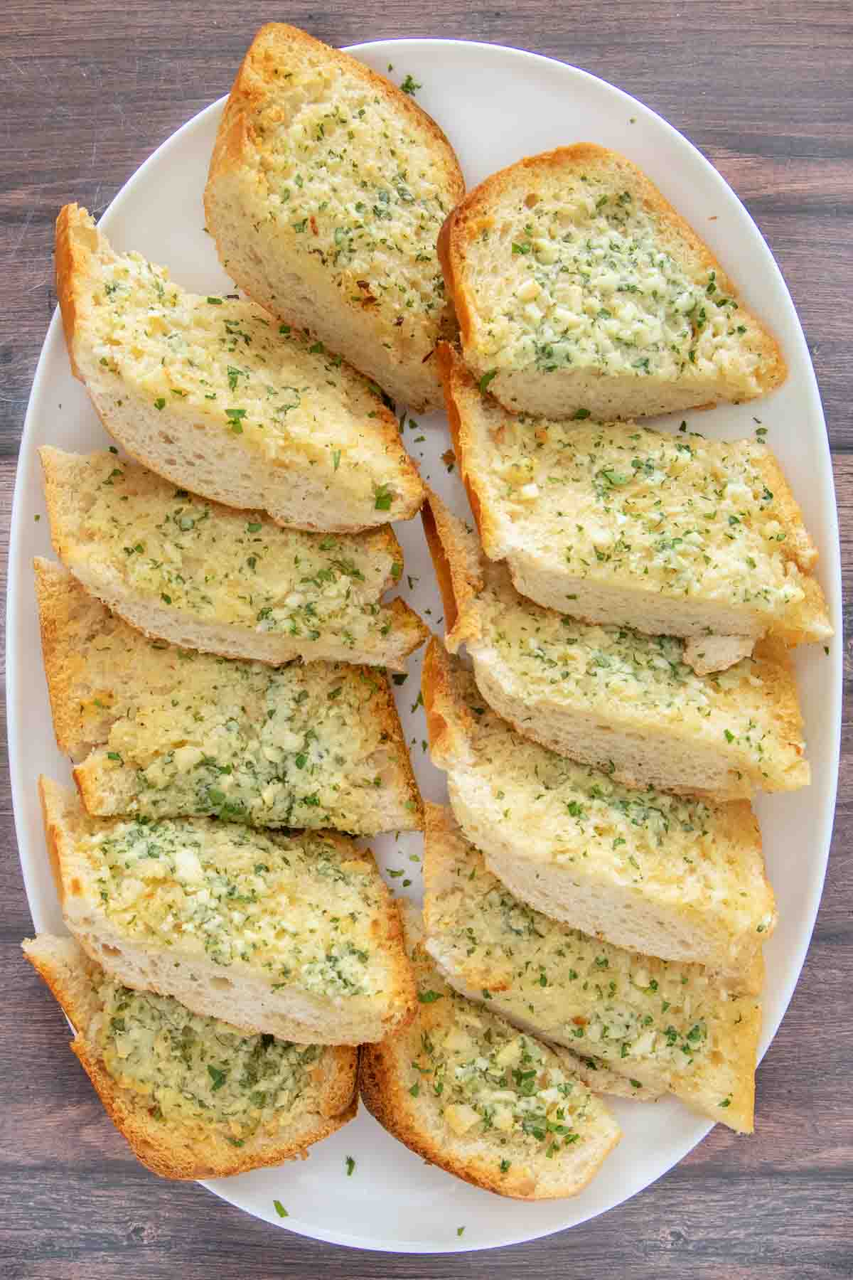 Sliced garlic bread on a white platter.